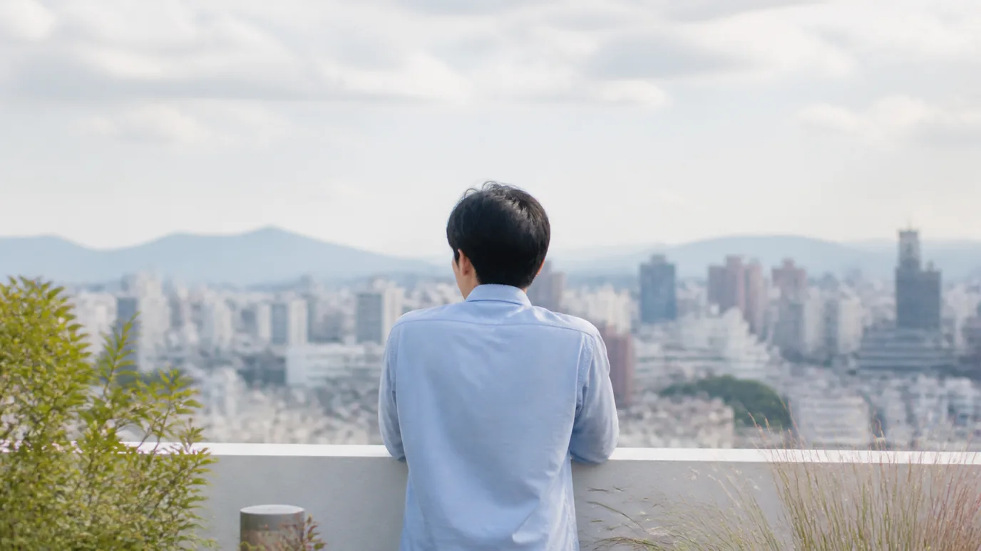 옥상 난간에서 도시 전경을 내려다보는 남성