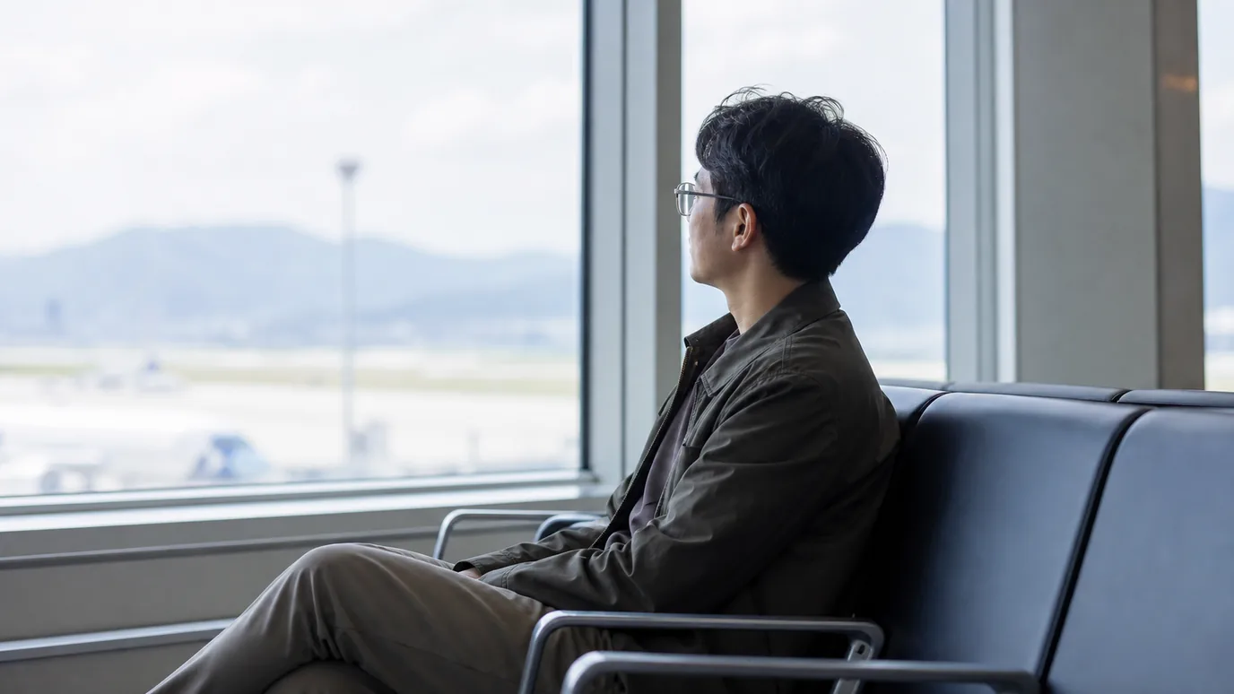 제주 공항 대기 공간에서 30대 한국인 성인이 안경을 쓴 채 휴식을 취하는 장면